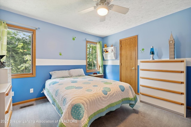 bedroom featuring ceiling fan, light colored carpet, and a textured ceiling