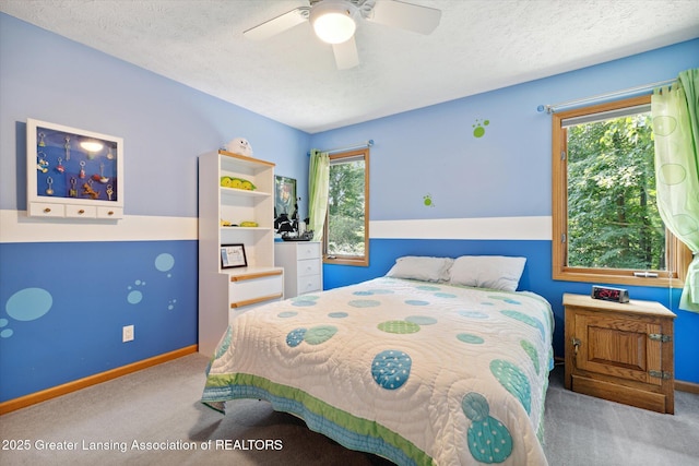 carpeted bedroom featuring ceiling fan, multiple windows, and a textured ceiling