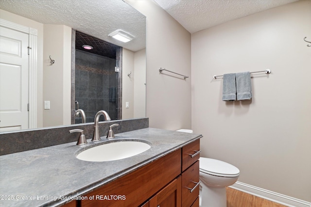 bathroom featuring vanity, toilet, a shower with door, and a textured ceiling