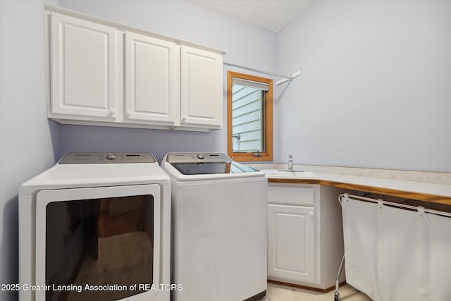 washroom featuring cabinets, washing machine and clothes dryer, sink, and a textured ceiling