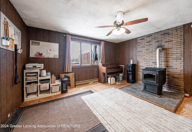 home office featuring a textured ceiling, wooden walls, ceiling fan, and a wood stove