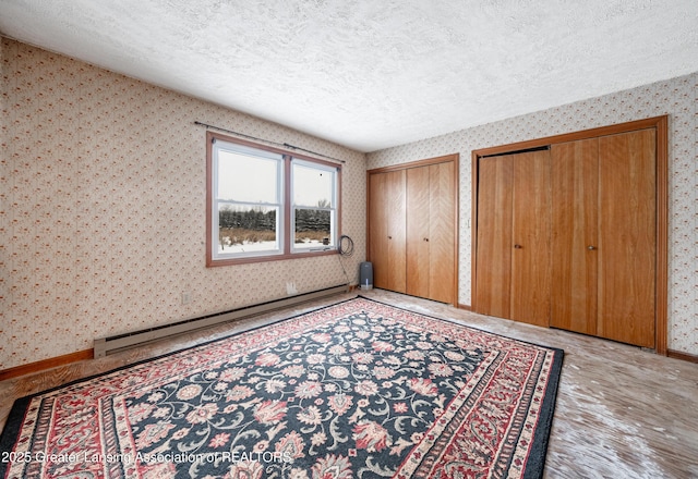 unfurnished bedroom with baseboard heating, light wood-type flooring, a textured ceiling, and two closets