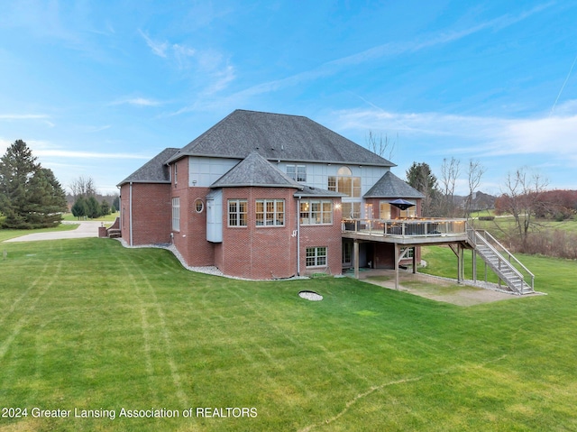 rear view of house with a deck, a patio, and a lawn