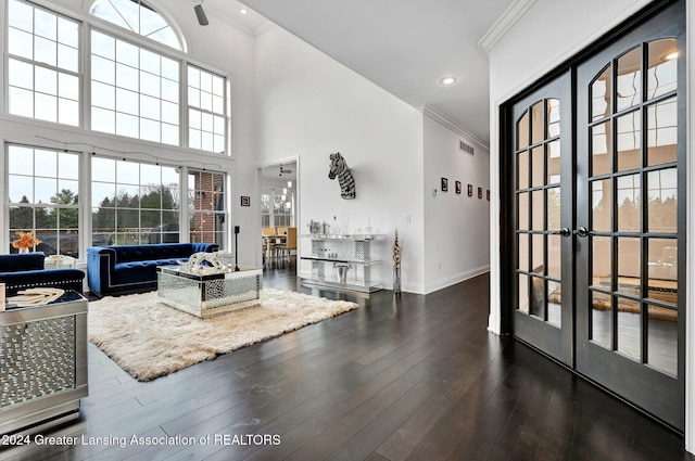 living room with a high ceiling, ornamental molding, a wealth of natural light, and dark hardwood / wood-style flooring