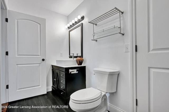 bathroom with wood-type flooring, vanity, and toilet