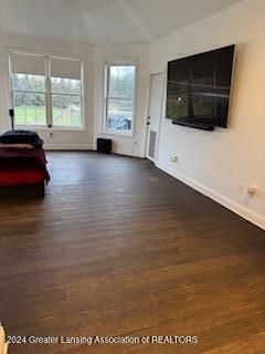 unfurnished living room with dark hardwood / wood-style floors and vaulted ceiling