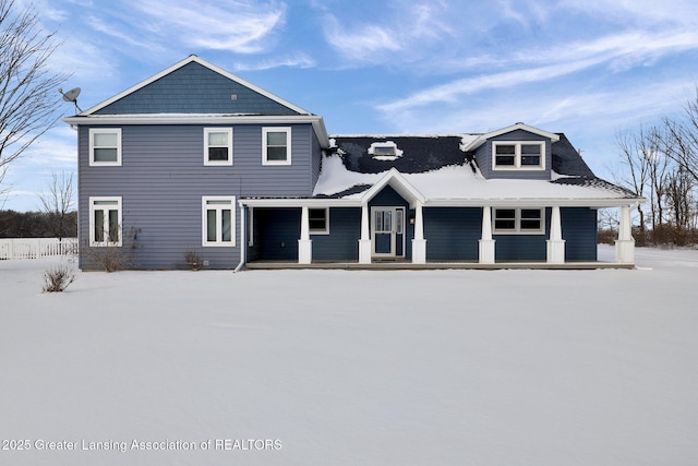 snow covered rear of property with covered porch