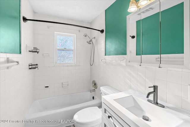 full bathroom featuring toilet, tiled shower / bath, backsplash, tile walls, and vanity