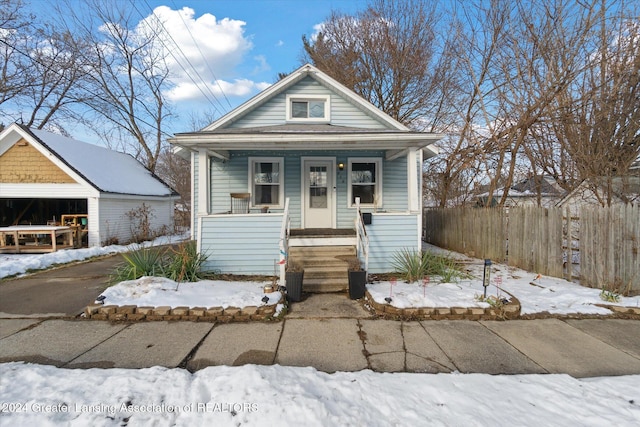 bungalow-style home with a garage, an outdoor structure, and covered porch