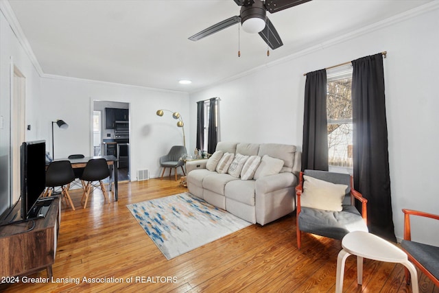 living room with hardwood / wood-style flooring, ornamental molding, and ceiling fan