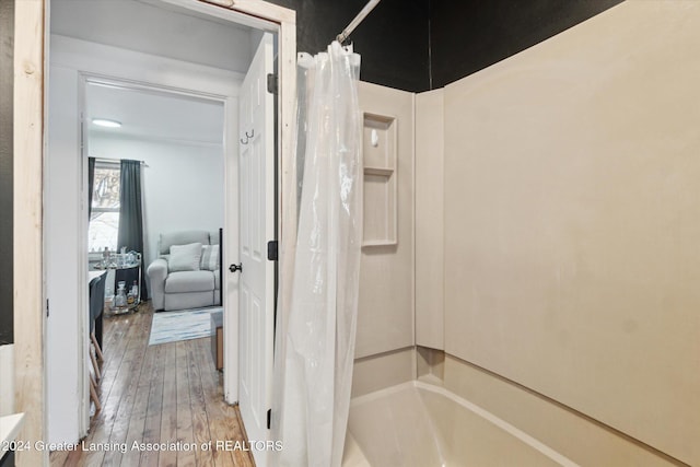 bathroom with hardwood / wood-style floors and shower / bath combination with curtain