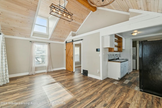 kitchen featuring a barn door, backsplash, black fridge, beam ceiling, and wooden ceiling