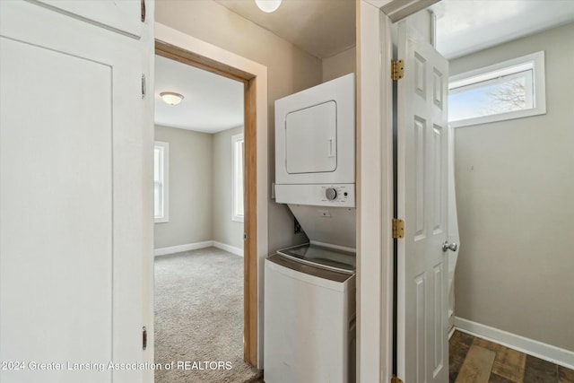 laundry room featuring stacked washer and clothes dryer, a healthy amount of sunlight, and carpet flooring