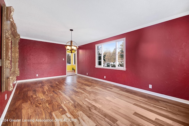 unfurnished dining area featuring wood-type flooring, crown molding, and an inviting chandelier