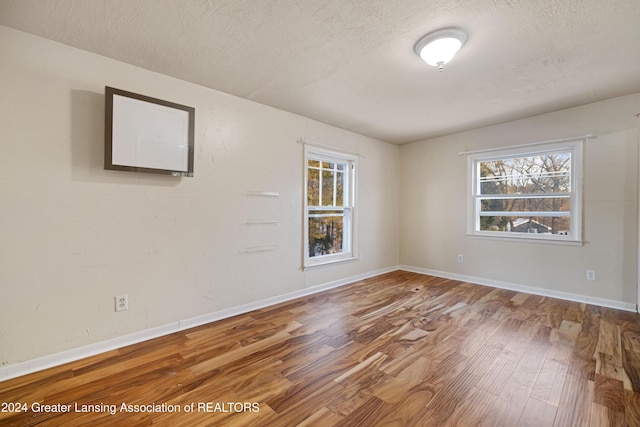 empty room with hardwood / wood-style flooring and a textured ceiling