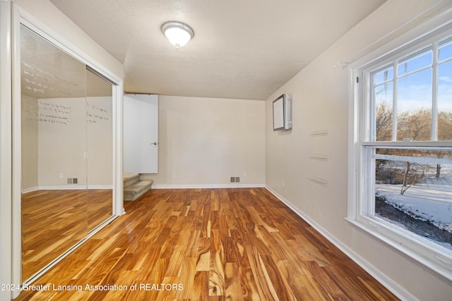 empty room with hardwood / wood-style floors and a textured ceiling