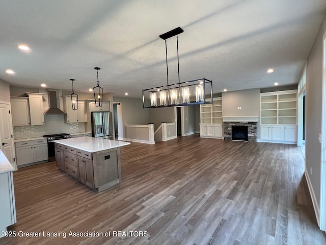 6097 Southridge Rd, East Lansing, MI 48823 - kitchen with stainless steel appliances, wall chimney exhaust hood, baseboards, light countertops, and dark wood-style flooring