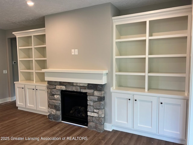 6097 Southridge Rd, East Lansing, MI 48823 - unfurnished living room featuring dark wood-type flooring, a fireplace, a textured ceiling, and baseboards