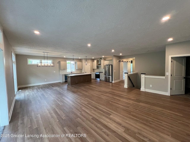 6097 Southridge Rd, East Lansing, MI 48823 - unfurnished living room with a textured ceiling, baseboards, dark wood-style flooring, recessed lighting, and a sink