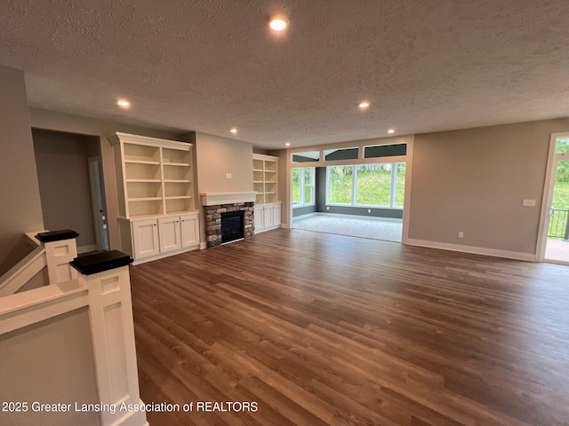6097 Southridge Rd, East Lansing, MI 48823 - unfurnished living room with a textured ceiling, dark wood-type flooring, recessed lighting, baseboards, and a fireplace