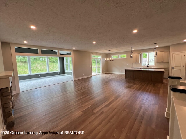 6097 Southridge Rd, East Lansing, MI 48823 - unfurnished living room featuring dark wood-style floors, recessed lighting, baseboards, a textured ceiling, and a chandelier