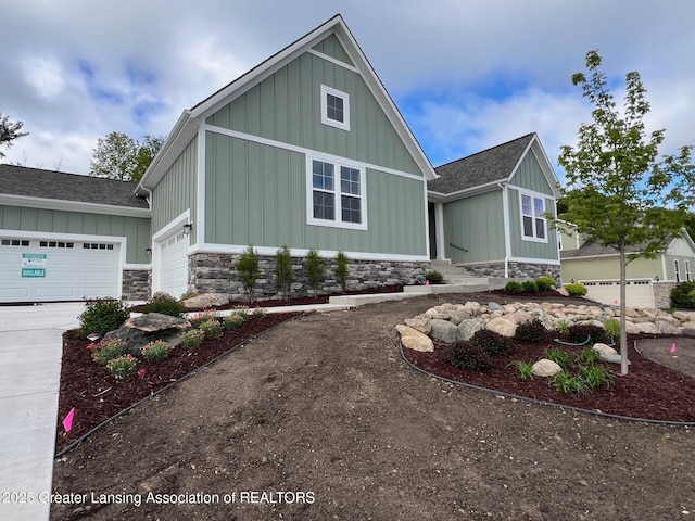6097 Southridge Rd, East Lansing, MI 48823 - craftsman inspired home featuring board and batten siding, a shingled roof, driveway, an attached garage, and stone siding