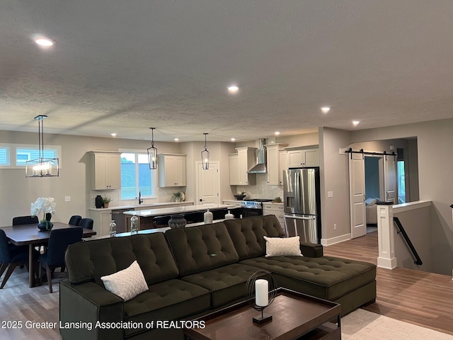 6097 Southridge Rd, East Lansing, MI 48823 - living area featuring a barn door, recessed lighting, wood finished floors, a chandelier, and a textured ceiling