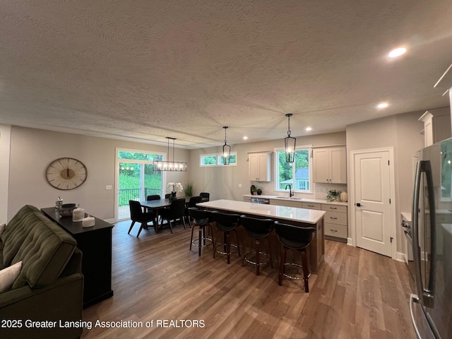 6097 Southridge Rd, East Lansing, MI 48823 - kitchen with freestanding refrigerator, light countertops, a kitchen island, wood finished floors, and recessed lighting