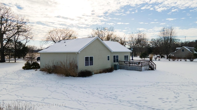 snow covered property with central AC unit and a wooden deck