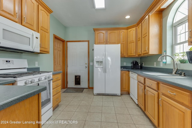 kitchen featuring sink, light tile patterned flooring, and white appliances