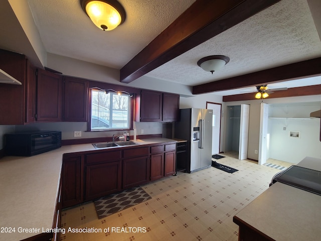 kitchen with stainless steel refrigerator with ice dispenser, sink, a textured ceiling, and beam ceiling