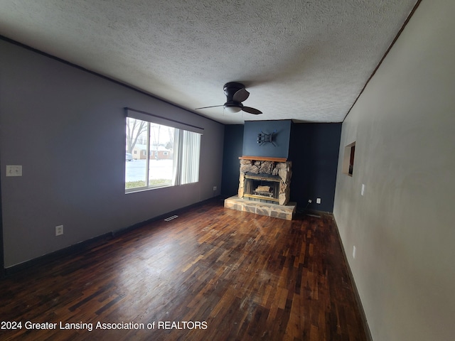 unfurnished living room featuring hardwood / wood-style flooring, ceiling fan, a textured ceiling, and a stone fireplace