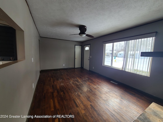 unfurnished living room featuring ceiling fan, dark wood-type flooring, and a textured ceiling