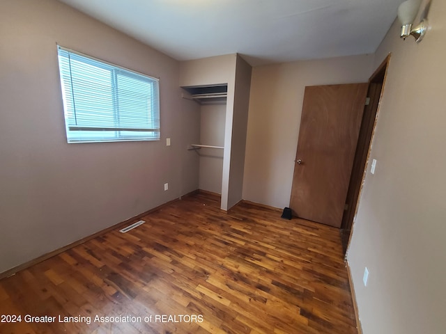 unfurnished bedroom with a closet and dark hardwood / wood-style floors