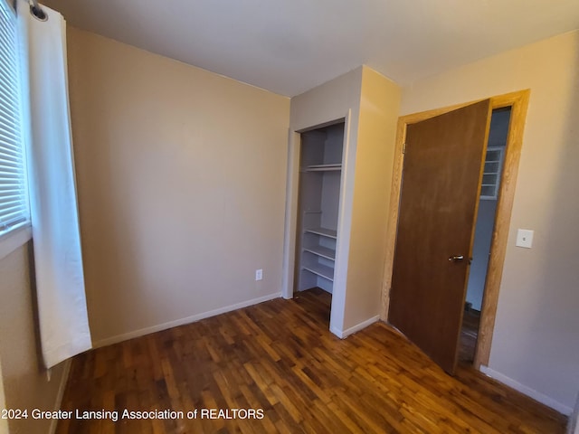 unfurnished bedroom featuring dark wood-type flooring and a closet