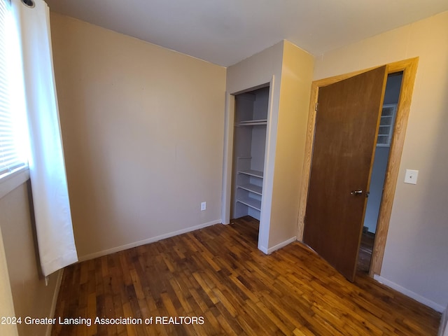 unfurnished bedroom featuring dark wood-type flooring and a closet