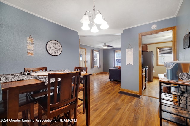 dining room with ceiling fan with notable chandelier, crown molding, and wood-type flooring