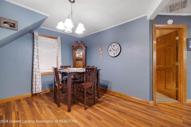 dining room featuring crown molding, wood-type flooring, vaulted ceiling, and an inviting chandelier