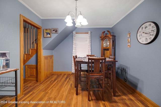 dining space with crown molding, hardwood / wood-style flooring, a chandelier, and lofted ceiling