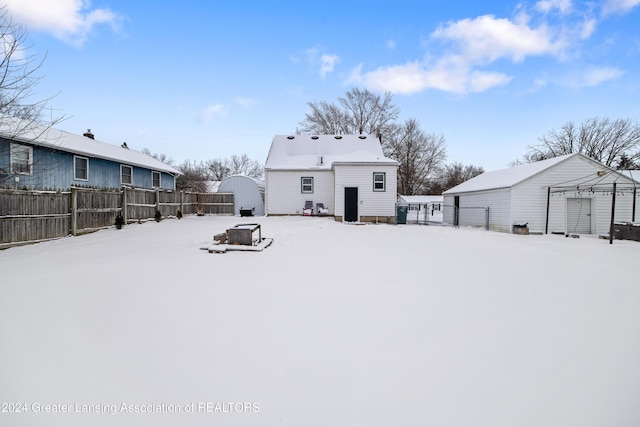 snow covered back of property featuring a storage shed