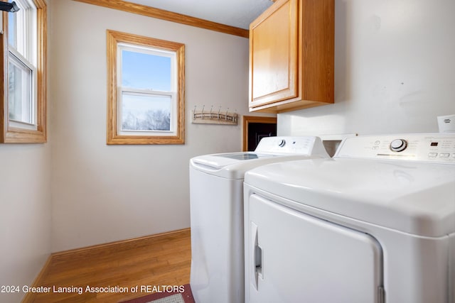 laundry area featuring light wood-type flooring, ornamental molding, cabinets, and independent washer and dryer