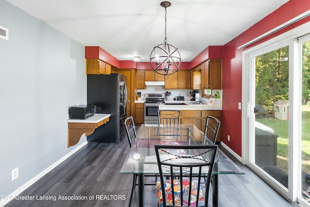 kitchen with pendant lighting, dark hardwood / wood-style flooring, a chandelier, and appliances with stainless steel finishes