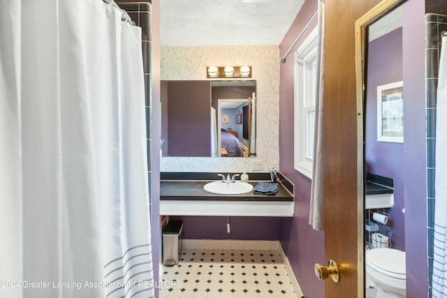 bathroom featuring a shower with curtain, toilet, and sink