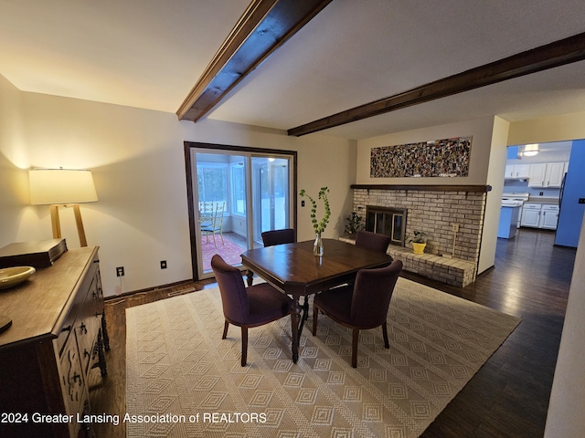 dining room with hardwood / wood-style flooring, a brick fireplace, and beamed ceiling