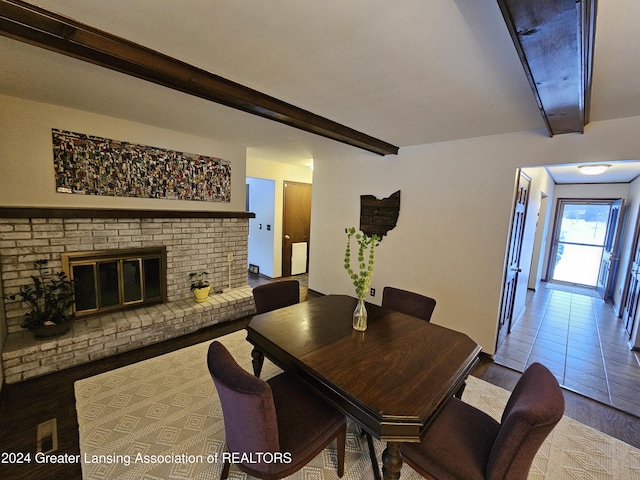 dining space with hardwood / wood-style flooring, beamed ceiling, and a fireplace