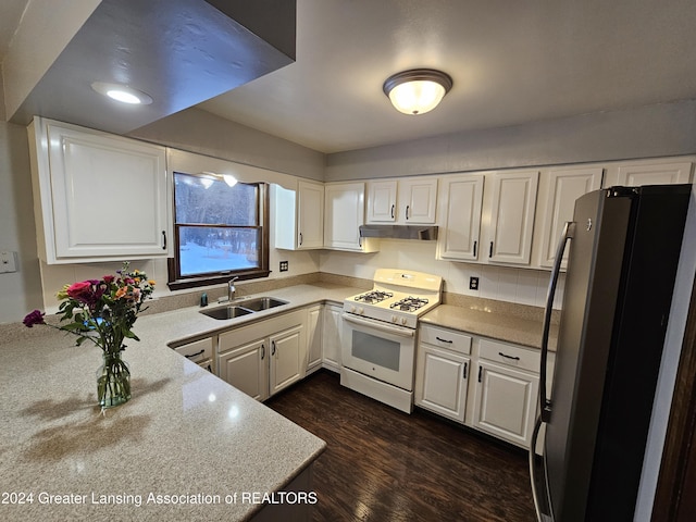 kitchen with white gas range oven, stainless steel refrigerator, white cabinets, sink, and dark hardwood / wood-style flooring