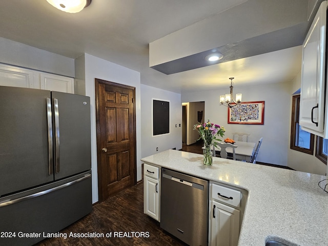 kitchen featuring hanging light fixtures, white cabinets, dark wood-type flooring, an inviting chandelier, and stainless steel appliances