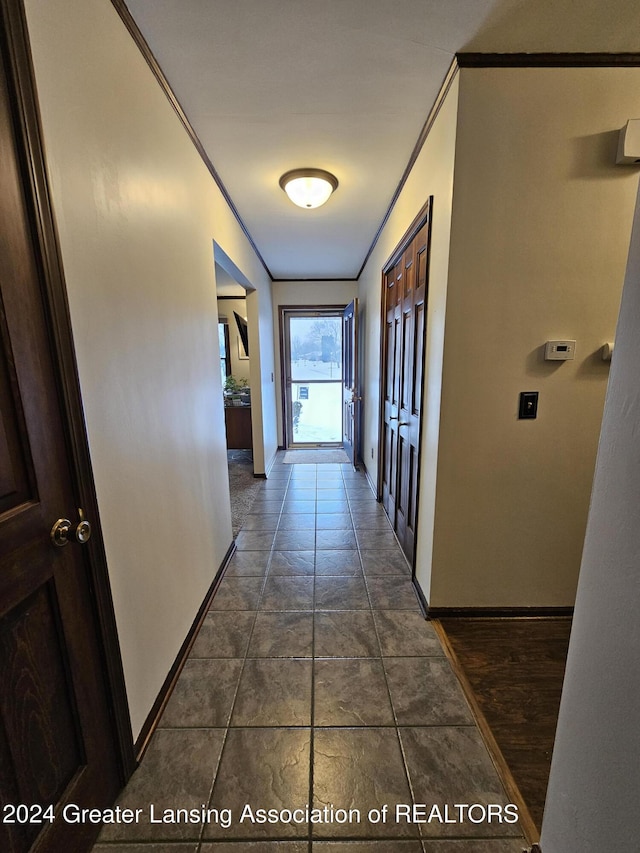 hallway with dark tile patterned floors and ornamental molding