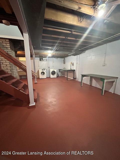 unfinished basement with stairway, washer and clothes dryer, and brick wall