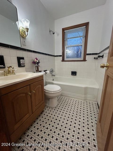 bathroom with toilet, vanity, a bathing tub, and tile walls